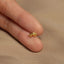 a person's hand holding a tiny gold ring