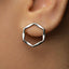 A close-up view of a person's ear wearing a silver hexagonal earring.