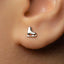 A close-up of a person's ear with a small silver earring featuring a skating shoe design.