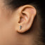 A small silver earring in the shape of a coffee cup is visible in the person's ear.