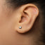 A close-up view of a person's ear with a small silver earring in the earlobe.