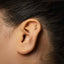 A close-up of a person's ear with a gold-colored earring featuring a snake-like design.