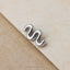 A silver-colored metal piece resembling a snake or snake is resting on a textured surface.
