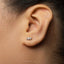 A close-up of a person's ear with a small silver earring in the earlobe.