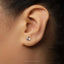 A close-up view of a person's ear with a small silver earring featuring a rabbit design.