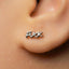 A close-up of a person's ear with a small, silver earring in the earlobe.