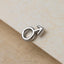 A silver male symbol charm is resting on a textured surface.