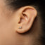 A close-up of a person's ear with a small silver earring in the earlobe.