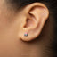 A small, silver earring with a small, red and black design is visible in the person's ear.