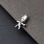 A small silver charm in the shape of a smiling face is resting on a textured gray surface.