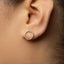 A close-up view of a person's ear, showing a simple silver hoop earring.