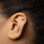 A close-up of a person's ear with a small gold earring in the earlobe.