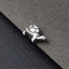 A silver-colored turtle charm is resting on a textured gray surface.