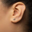 A close-up of a person's ear with a small, silver earring featuring a star-like design.