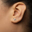 A close-up of a person's ear with a small silver earring featuring a small dog-like figure.