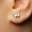 A close-up view of a person's ear adorned with a small, silver earring.