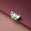 A silver earring with a unique, textured design rests on a textured purple surface.