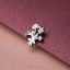 A silver flower brooch is resting on a textured purple surface.