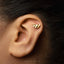A close-up of a person's ear with a small gold-colored earring in the earlobe.