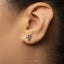 A close-up of a person's ear with a small, silver earring featuring a floral design.
