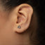 A close-up of a person's ear with a small silver earring in the earlobe.