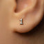 A close-up of a person's ear with a small silver earring featuring the number 1 on it.