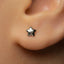 A close-up of a person's ear with a small silver star-shaped earring in the earlobe.
