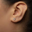 A close-up of a person's ear with a small heart-shaped earring in the earlobe.