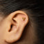 A gold-colored earring with a triangular design is visible in the image.