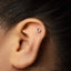 A close-up view of a person's ear with a small silver hoop earring inserted in the earlobe.