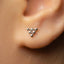 A close-up view of a person's ear, showing a small, triangular-shaped earring with a geometric design.