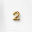 A single, shiny gold number 2 is prominently displayed against a white background.