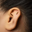 A gold earring with a symbol on it is visible in the image.
