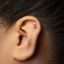 A close-up of a person's ear with a small number 2 stud in the earlobe.