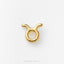 A single, shiny gold-colored charm in the shape of a zodiac sign, specifically a Taurus symbol, is shown against a white background.