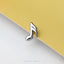 A silver music note-shaped earring is resting on a yellow surface.