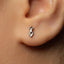 A close-up of a person's ear with a small silver earring in the earlobe.