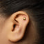 A close-up of a person's ear with a small gold star-shaped earring in the earlobe.