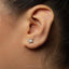 A close-up view of a person's ear adorned with a small silver earring featuring a dragon design.