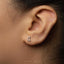 A close-up view of a person's ear with a small silver earring featuring a crescent moon design.