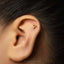 A gold-colored earring with the letter "P" on it is visible in the image.