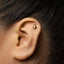 A close-up of a person's ear with a small gold earring in the earlobe.