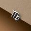 A silver-colored metal charm in the shape of the zodiac sign "Virgo" is shown against a beige background.
