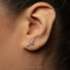 a close-up view of a person's ear with a small, silver earring featuring a design resembling a brain or nervous system.
