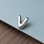 A silver letter 'V' is placed on a blue surface.
