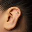 A close-up of a person's ear with a small silver letter V stud in the earlobe.