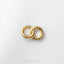 A pair of gold-colored rings or earrings are displayed against a white background.