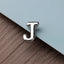 A close-up image of a metallic letter "J" on a textured surface.