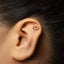 A close-up of a person's ear with a small gold earring in the earlobe.
