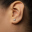 A close-up of a person's ear with a small, silver earring in the earlobe.